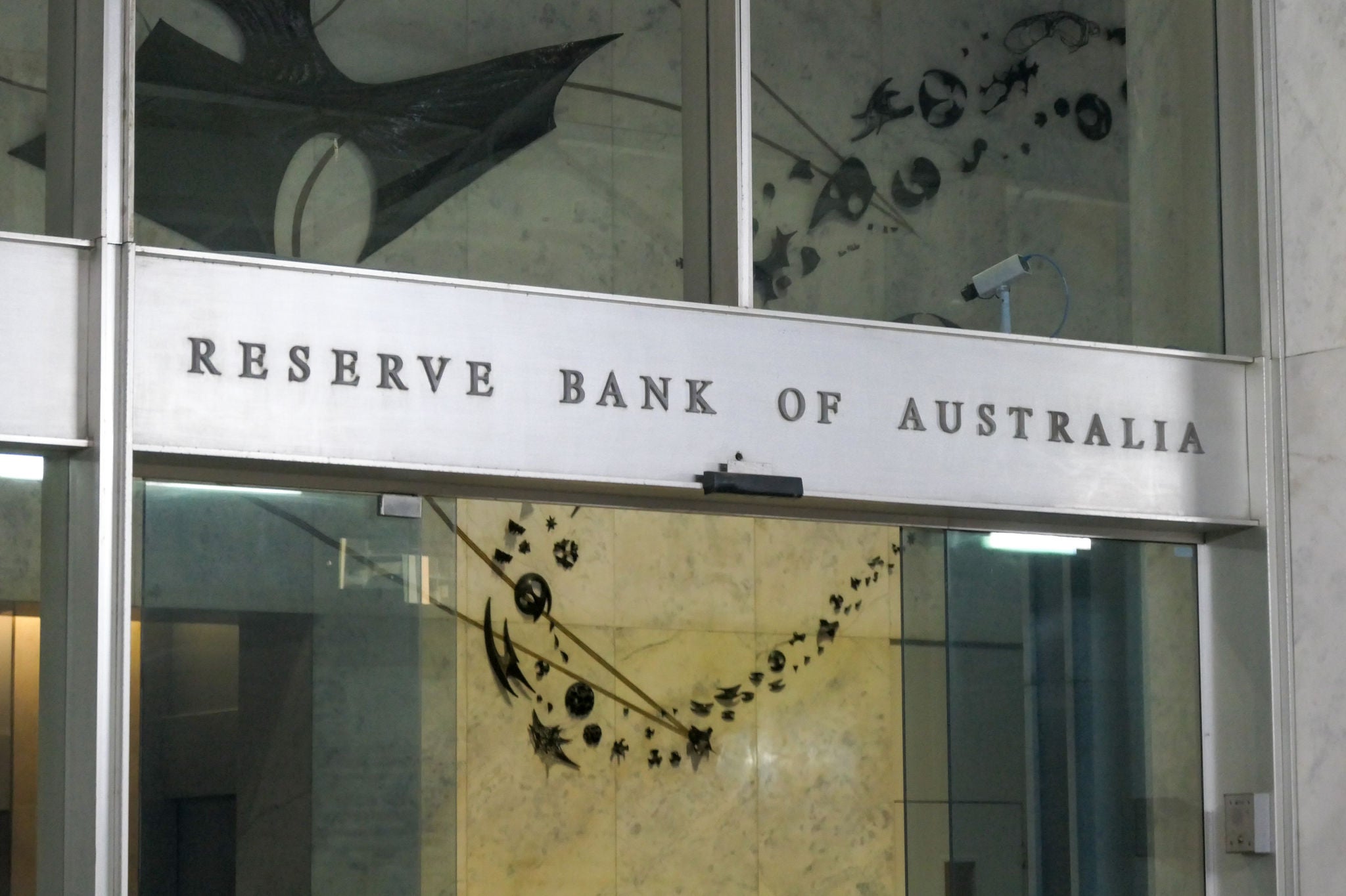 The main pedestrian entrance of the Reserve Bank of Australia building at 65 Martin Place in the central business district (CBD) of Sydney.  The automatic glass doors are briefly open.  Three armed guards (not shown here) guard the foyer.  This image was taken from outside the building in Martin Place, looking through the glass facade, on an overcast afternoon on 6 October 2023.