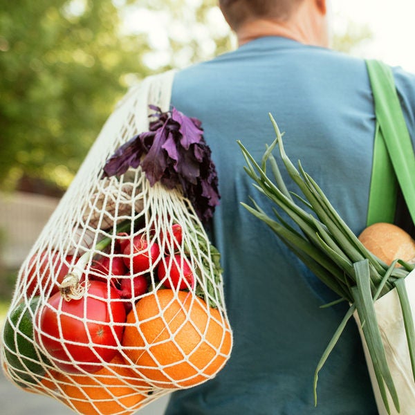 Senior man carrying fruits and vegetables in reusable shopping bag and mesh bag, environment conservation and sustainability concept