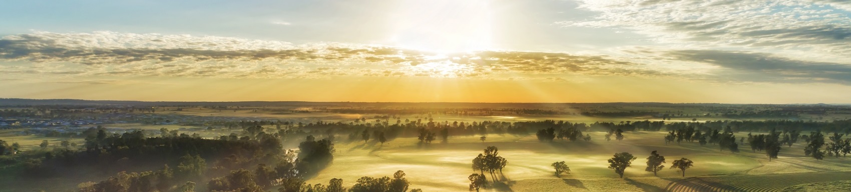 Secluded farm homestead on agriculture cultivated fields near Macquarie river in Dubbo town of Australia - aerial sunrise view.
